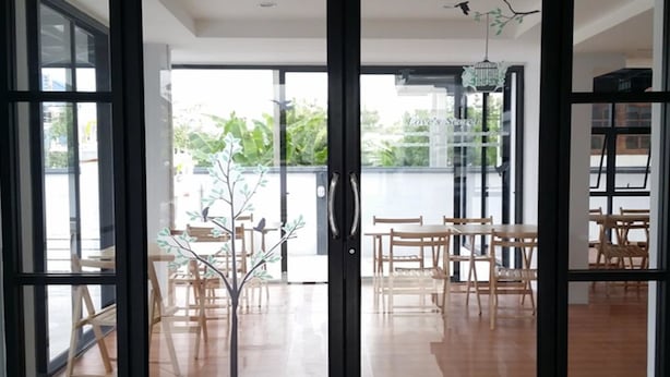 Um interior moderno com uma porta de vidro que dá para uma área externa com móveis de madeira e uma árvore decorativa.