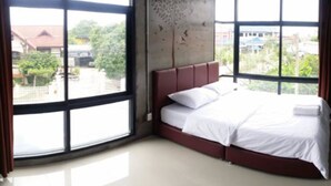 Quarto com cama, guarda-roupa e grandes janelas.