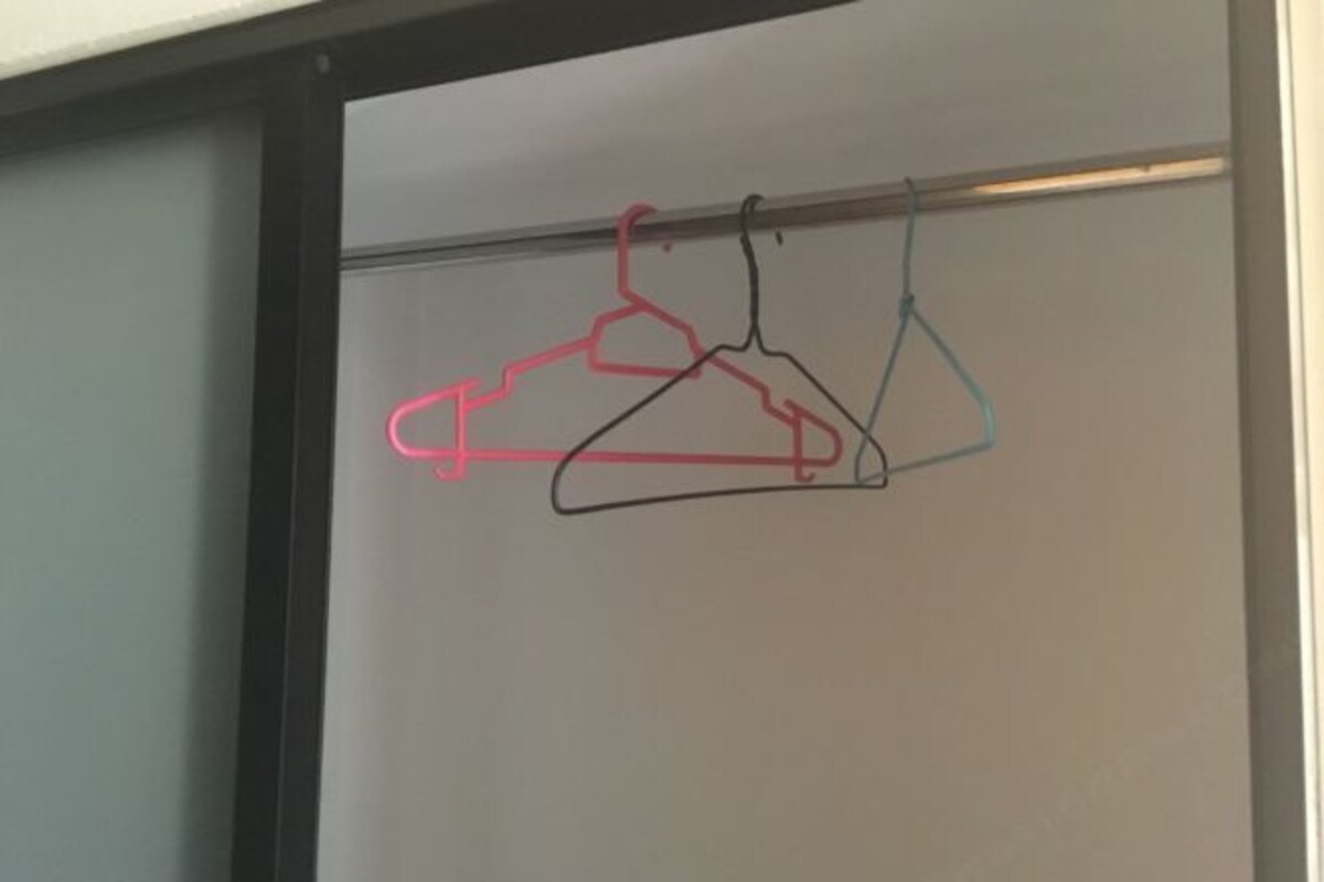 En whiteboardtavla med tre upphängningsanordningar i färgerna rosa, svart och blå.