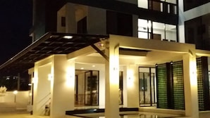 Um edifício moderno com entrada coberta, portas de vidro e escadaria que leva ao nível superior.