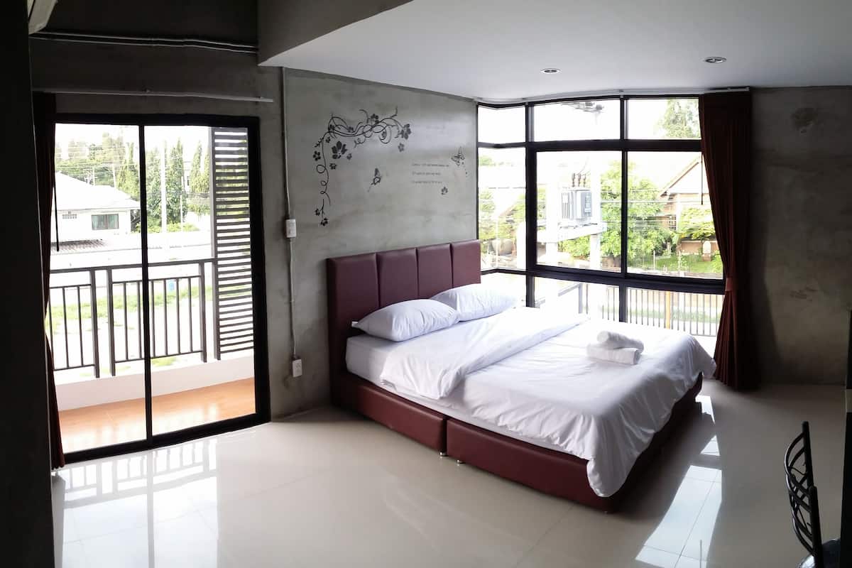 Un dormitorio moderno con una cama grande, un balcón y vistas al exterior.