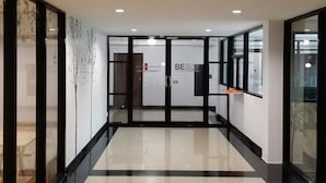 Um lobby de hotel moderno com entrada por porta de vidro, balcão de recepção e piso limpo e reluzente.