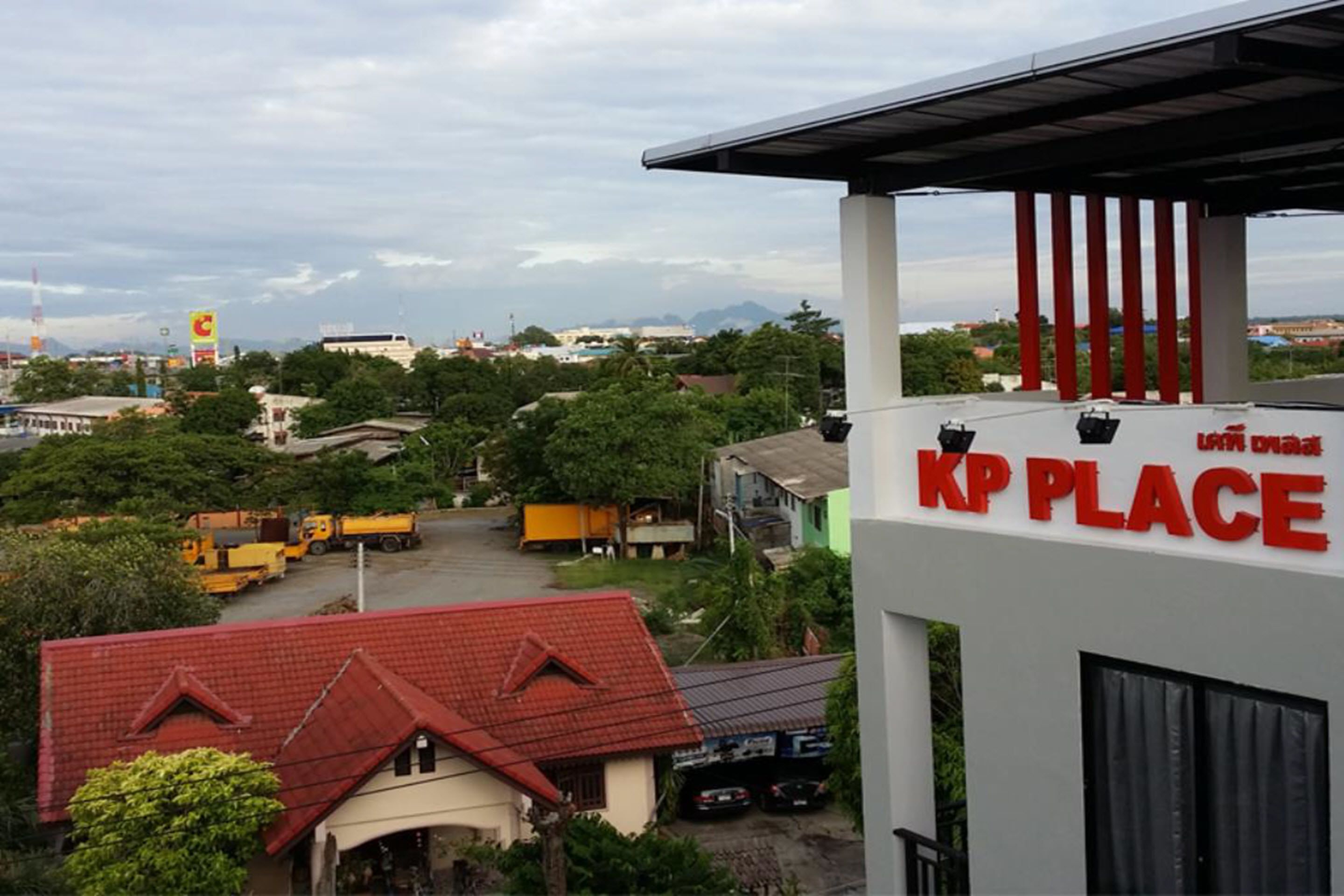 A commercial building with a sign reading "KP PLACE" and a view of surrounding buildings and greenery.