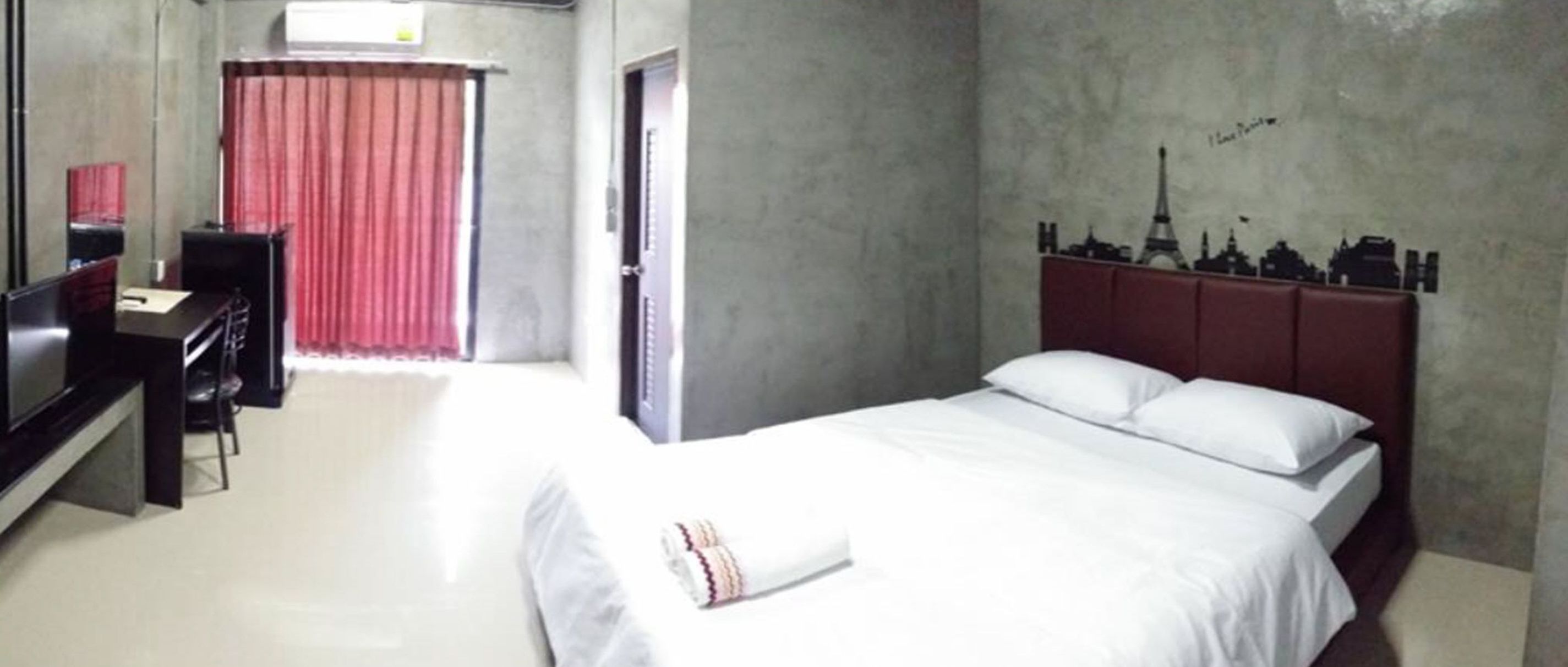 A hotel room with a bed, a desk, and a mirror.