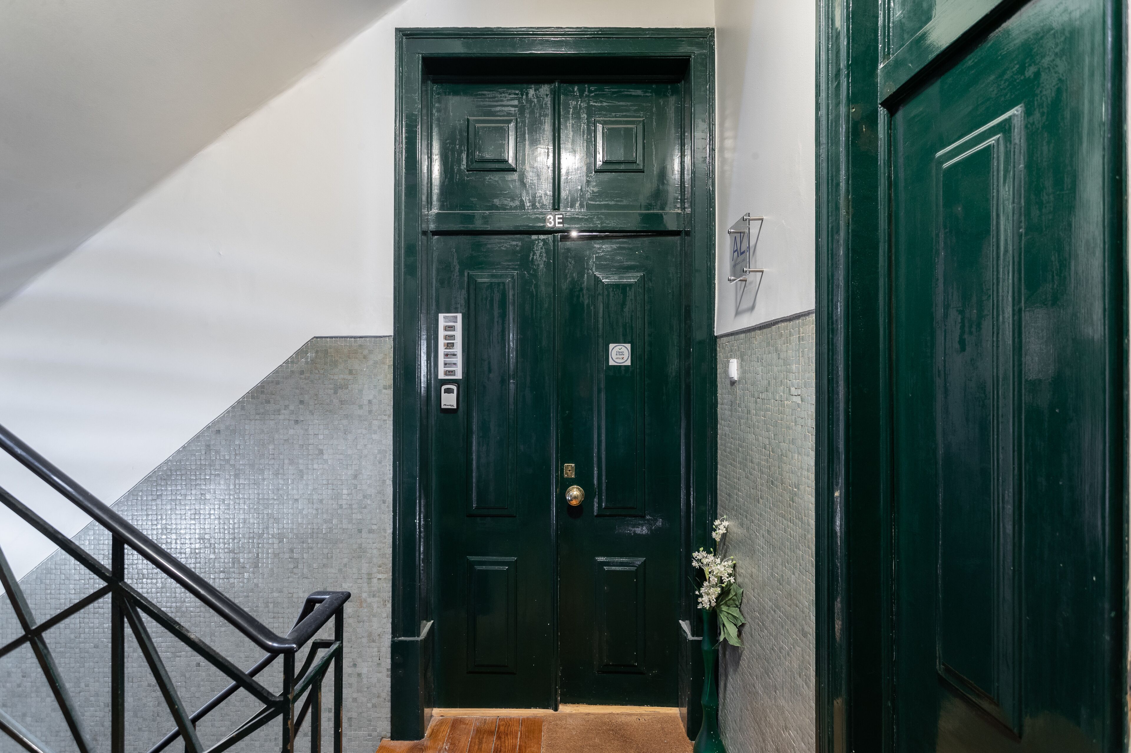 Una puerta doble de color verde oscuro con un tirador de latón y una pequeña señal encima.