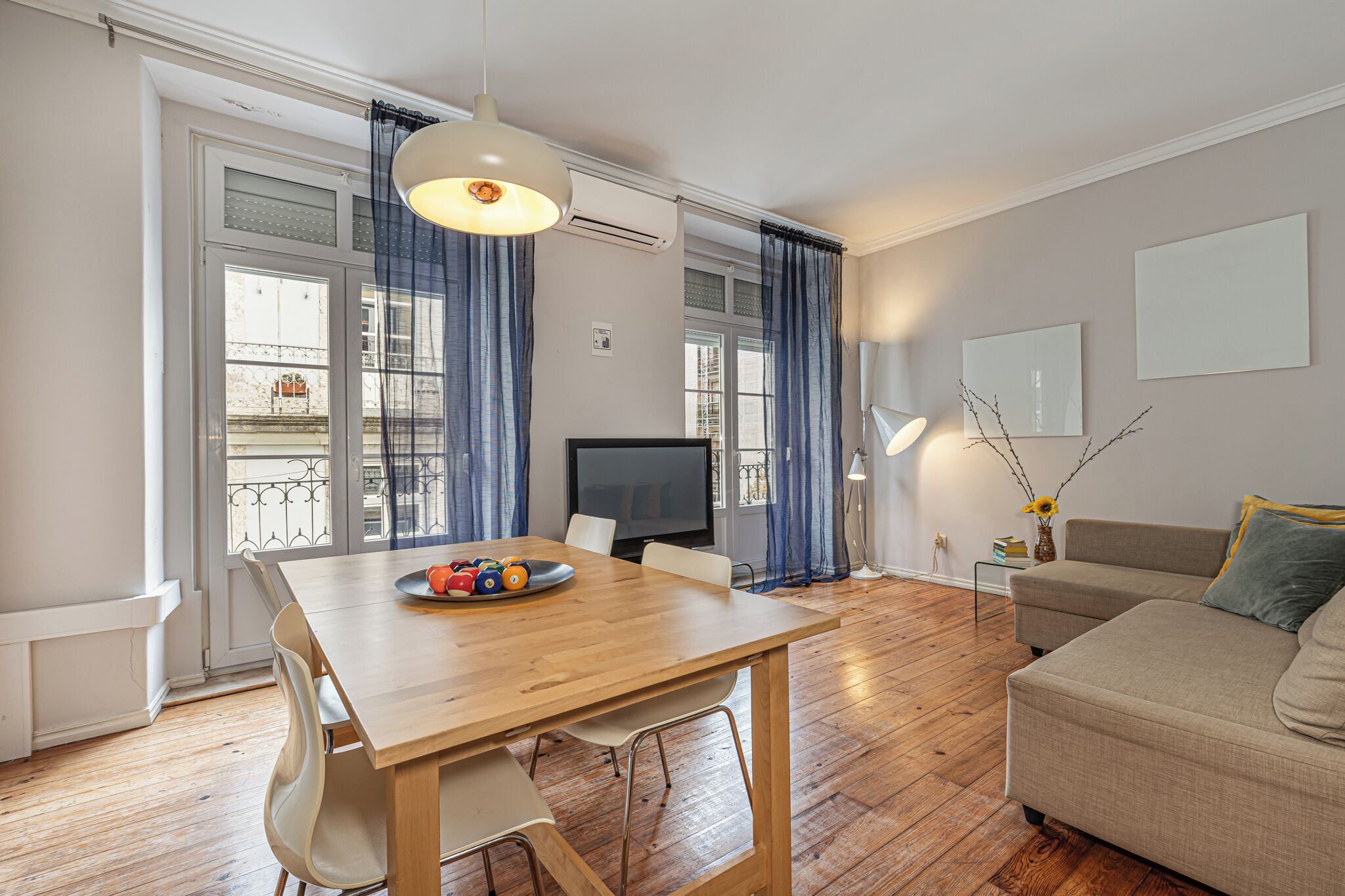 Una sala de estar moderna con una mesa de comedor de madera, un sofá y un televisor.