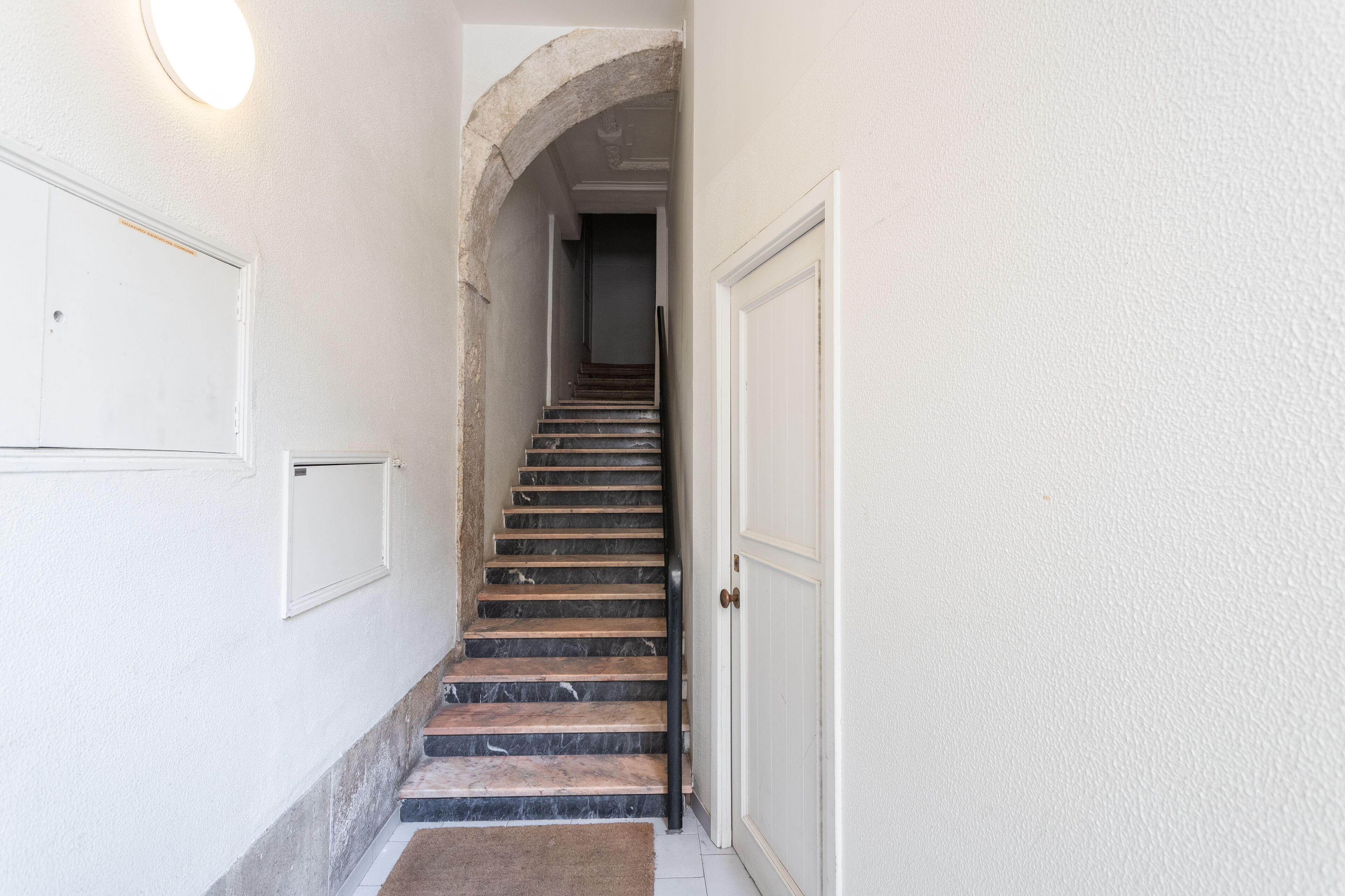 Una escalera con un arco de piedra que conduce a una puerta.