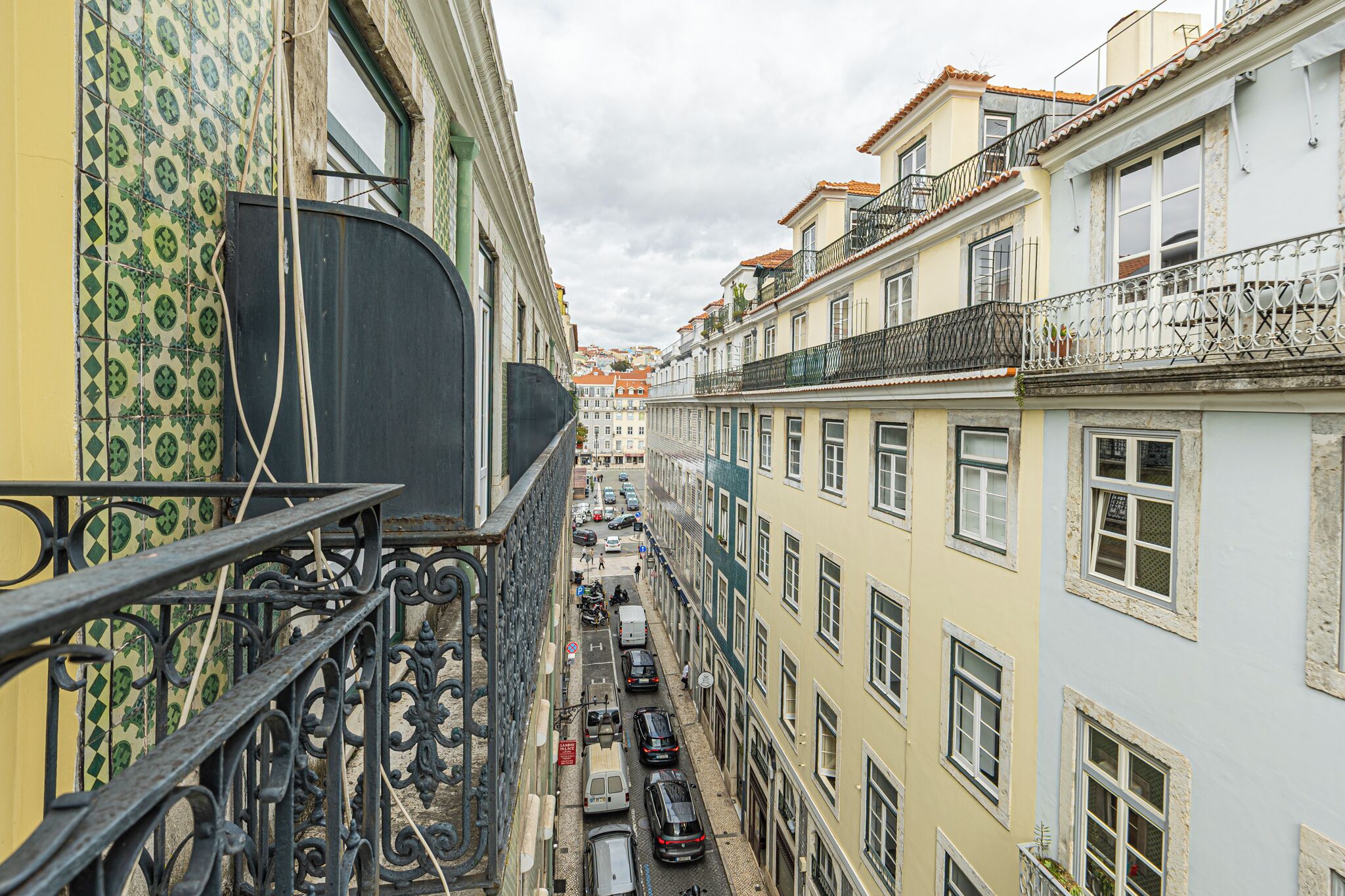 A narrow street lined with multi-story buildings, featuring balconies and a variety of architectural styles.