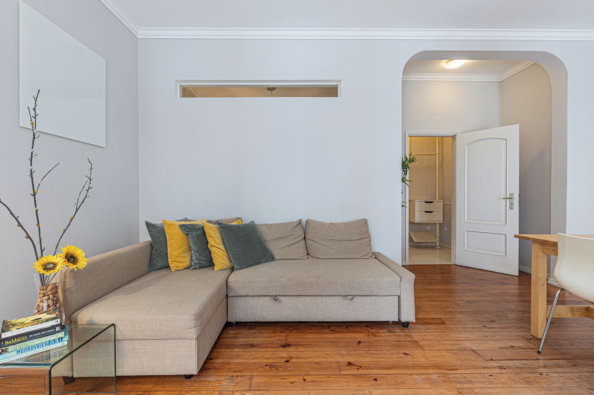 Un salon avec un canapé d’angle beige, une table basse en verre et un plancher en bois.