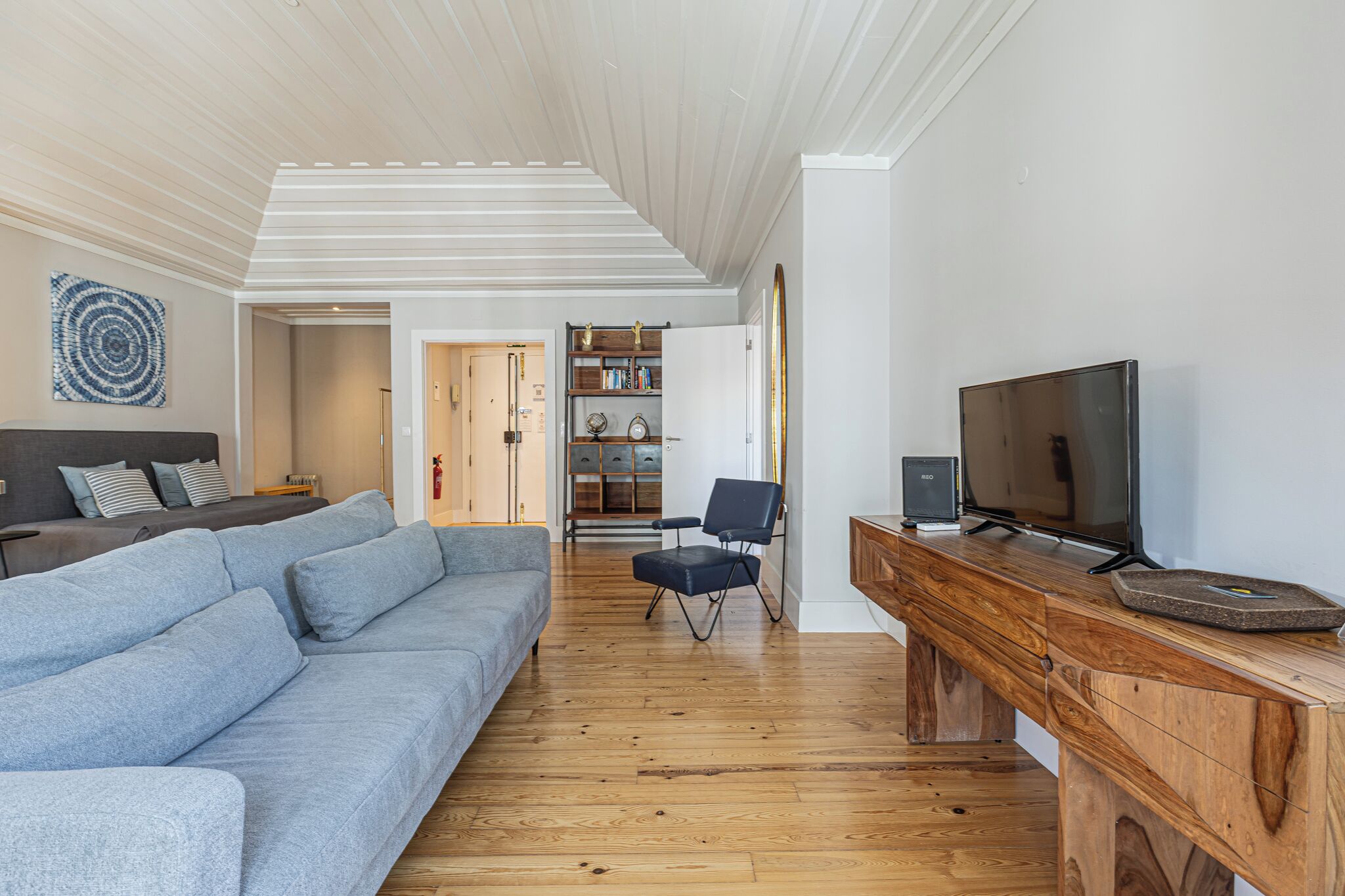 A modern living room with a grey sofa, wooden coffee table, and a TV on a wooden stand.