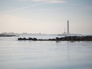 Un faro junto al agua, con costas rocosas y un cielo brumoso.