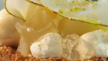 Un dessert surmonté d’une crème onctueuse, d’une tranche de citron et décoré d’herbes fraîches.