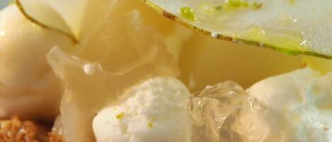 A dessert with a creamy topping, a slice of lemon, and a garnish of green herbs.