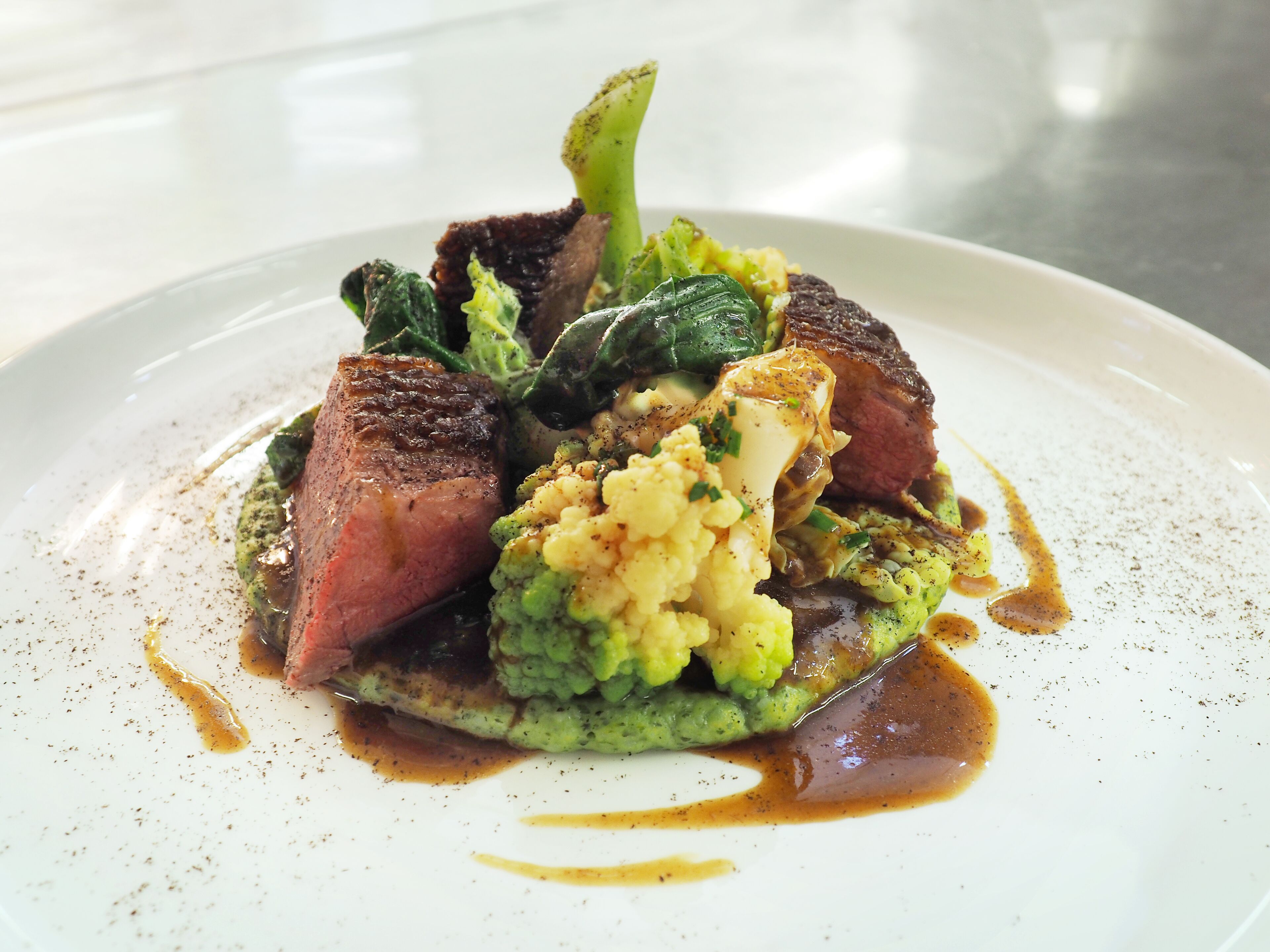 Une assiette de nourriture comprenant un steak, de la purée de pommes de terre et des légumes.