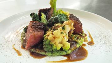 Une assiette de nourriture comprenant un steak, de la purée de pommes de terre et des légumes.