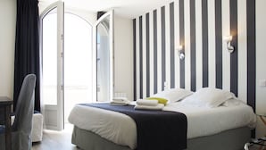 Una habitación de hotel con cama, una silla, una mesita de noche y una ventana con cortinas.