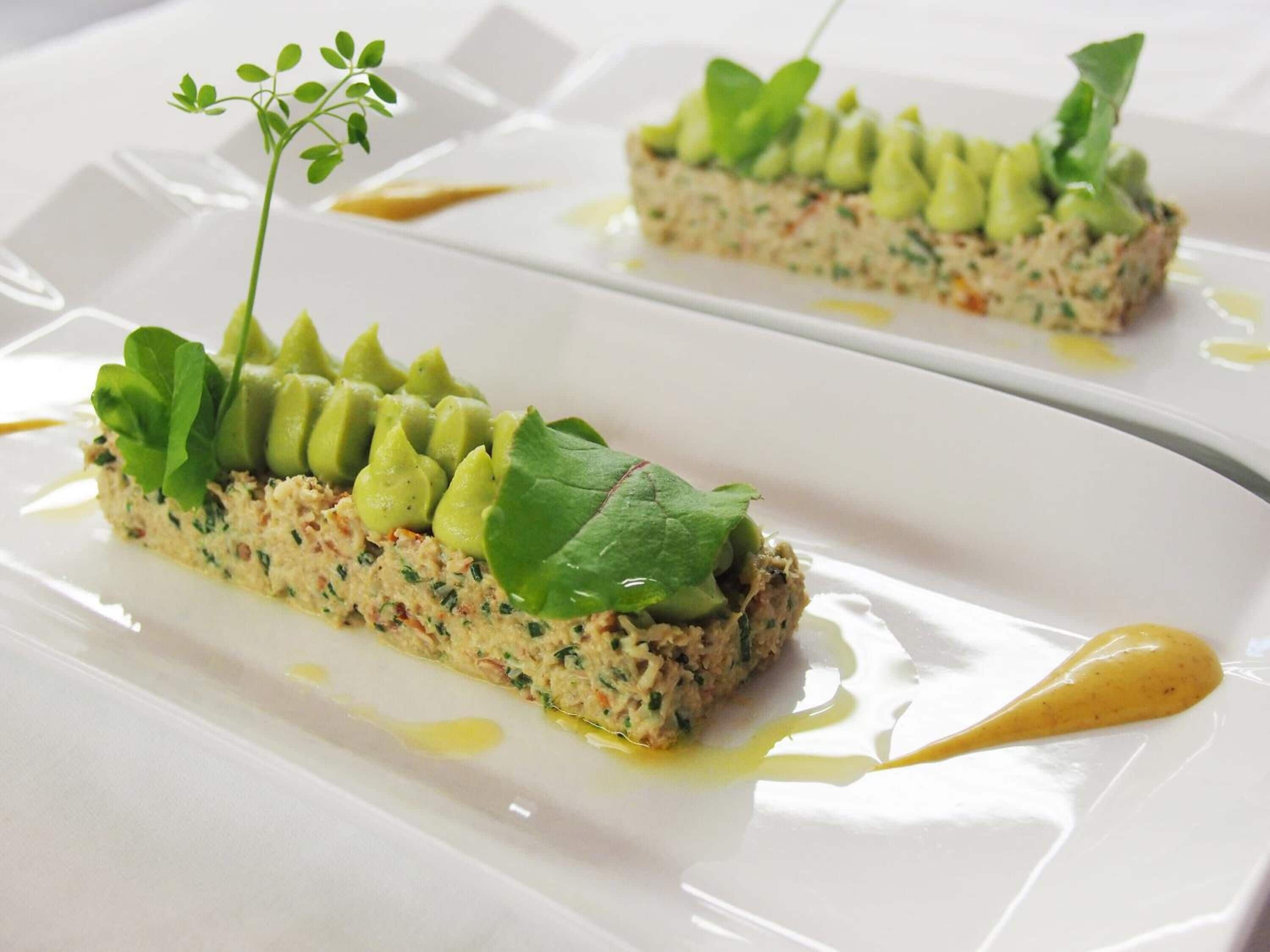 Un plato con aguacate y verduras, servido en un plato blanco con salsa.