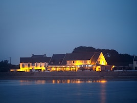 Um hotel com uma placa visível, vista para o mar e superfície aquática refletora.