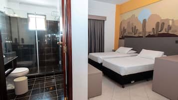 A hotel room with a shower, toilet, and two beds.