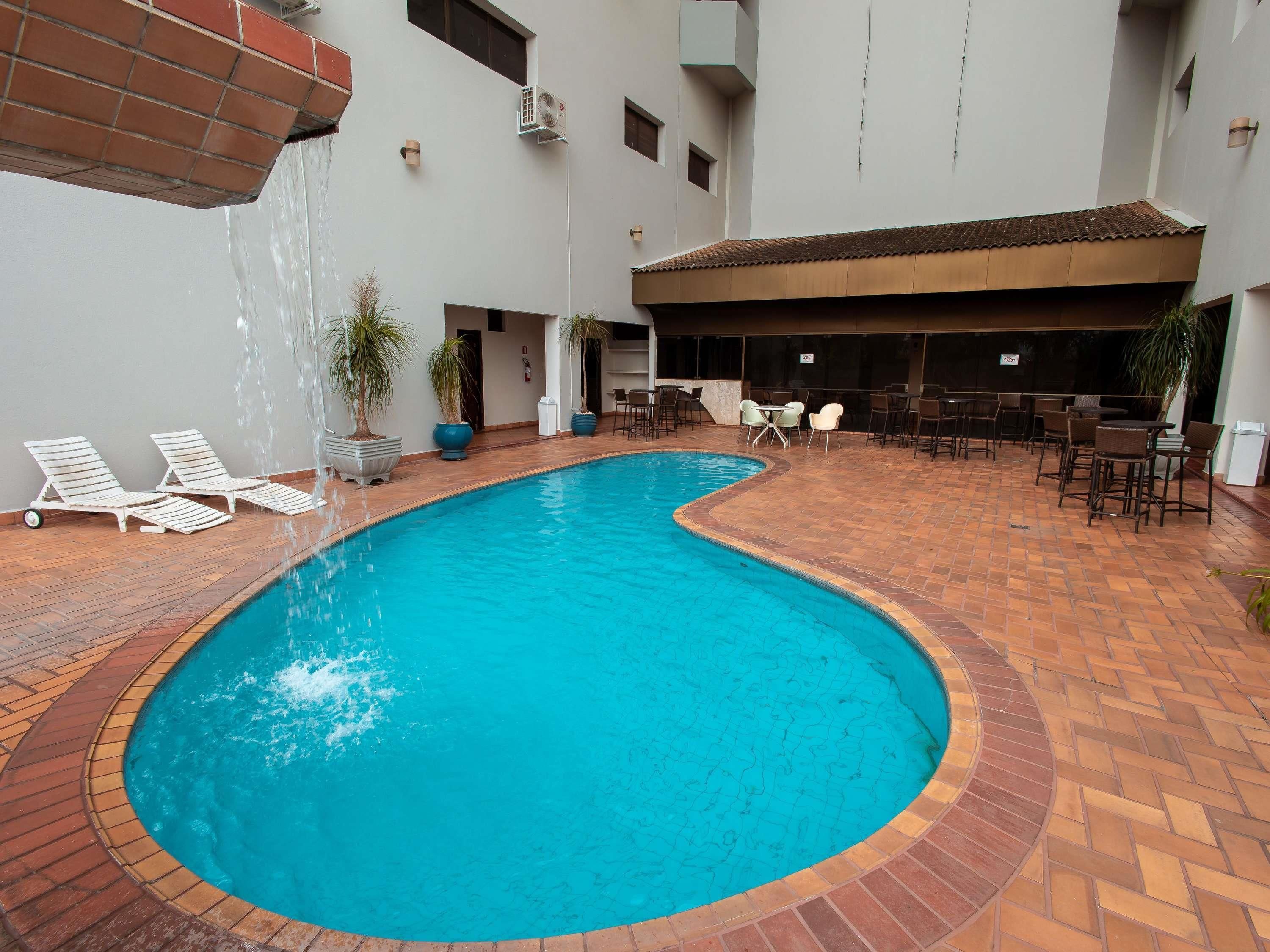A swimming pool with lounge chairs and a covered seating area.