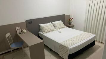 A hotel room with a bed, a desk, and a chair.
