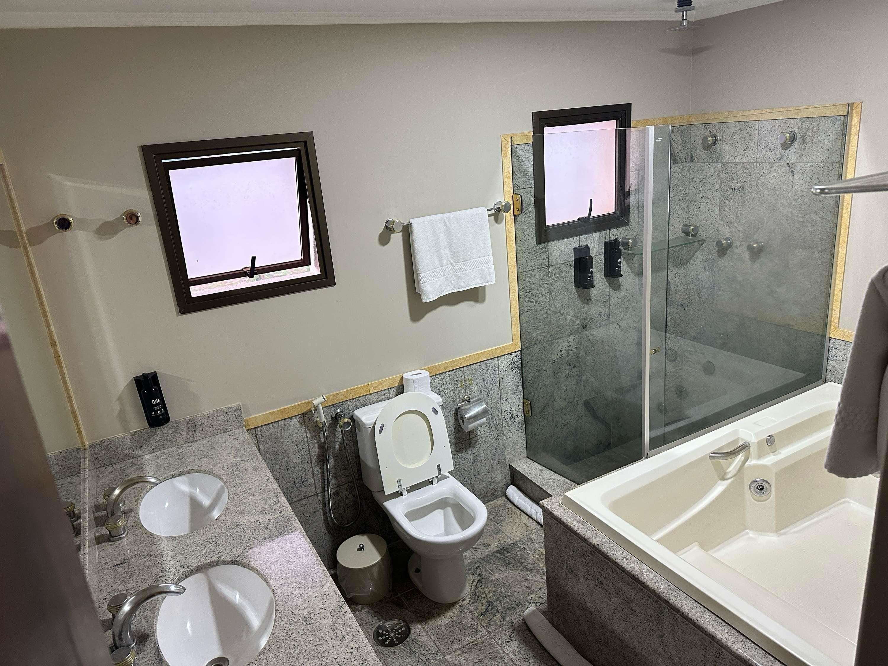 A bathroom with a toilet, bidet, two sinks, a shower, and a bathtub.