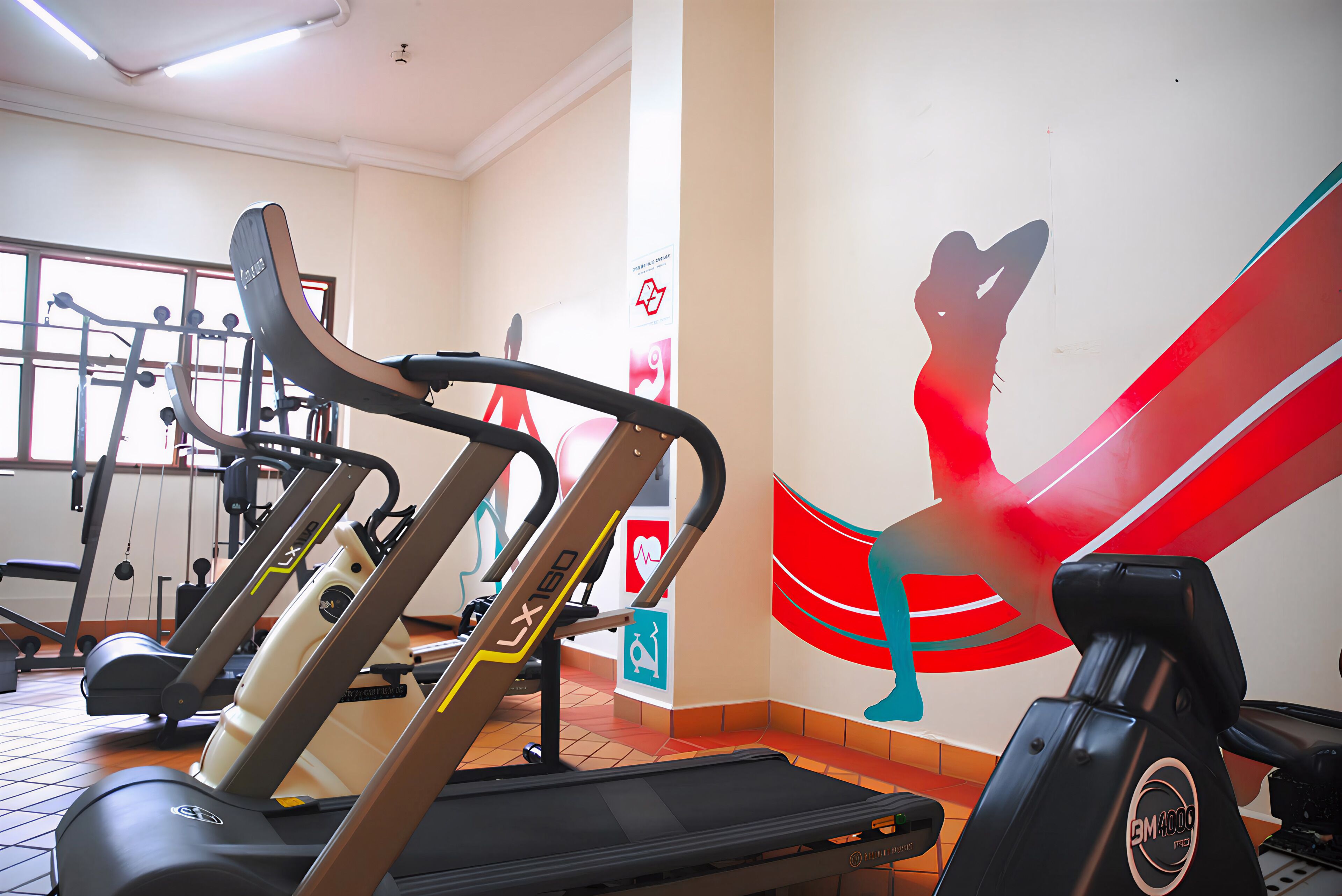 Un gimnasio con cintas de correr, bicicletas estáticas y máquinas de pesas.