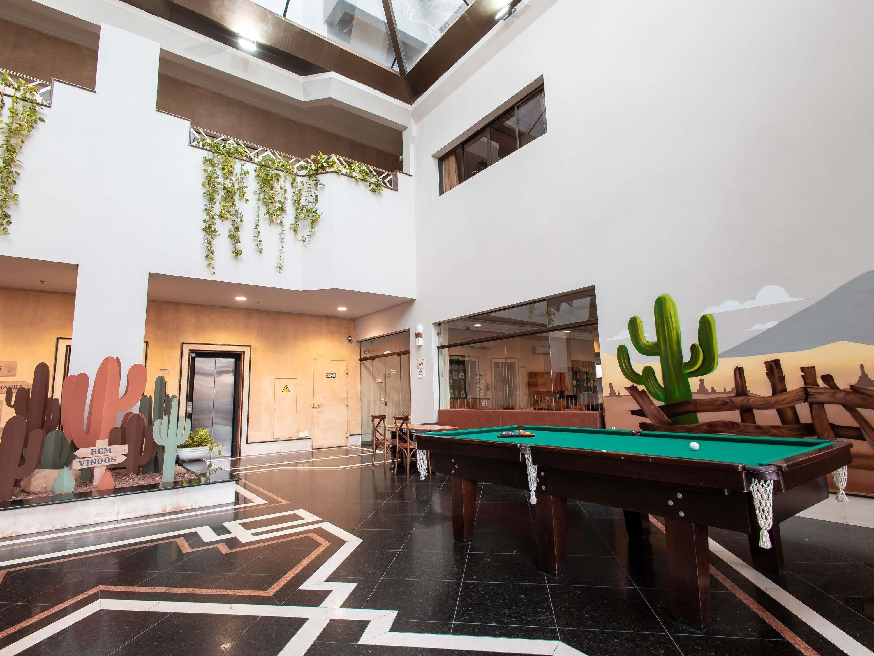 A spacious indoor area with a pool table, a cactus decoration, and a desert mural.