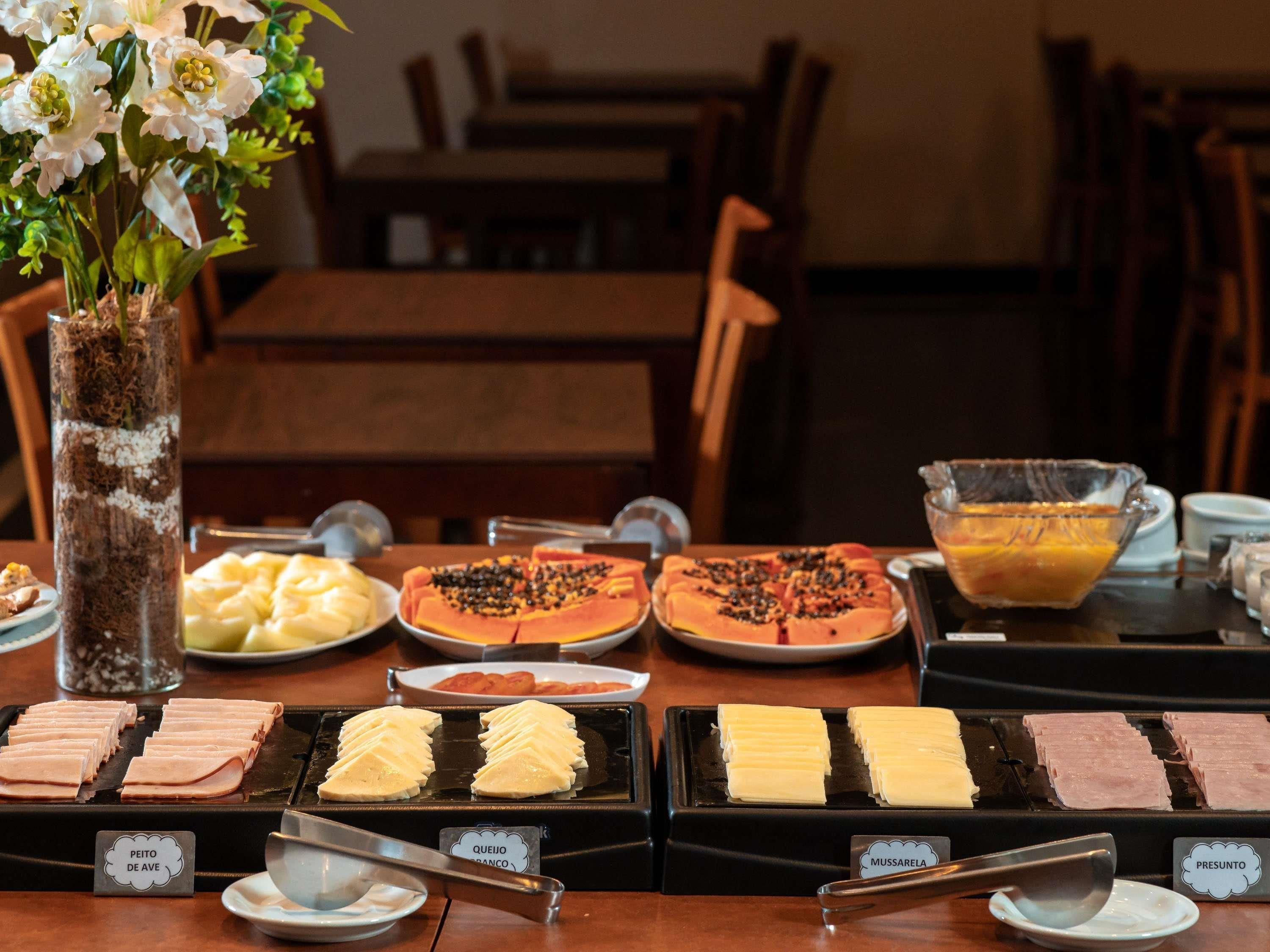 A buffet with various food options including meats, cheeses, and fruits.