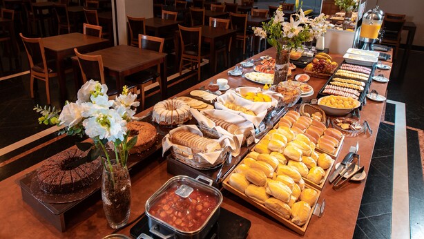 Un bufet amb diversos plats i una estació de cafè en una sala de dinar amb taules i cadires.