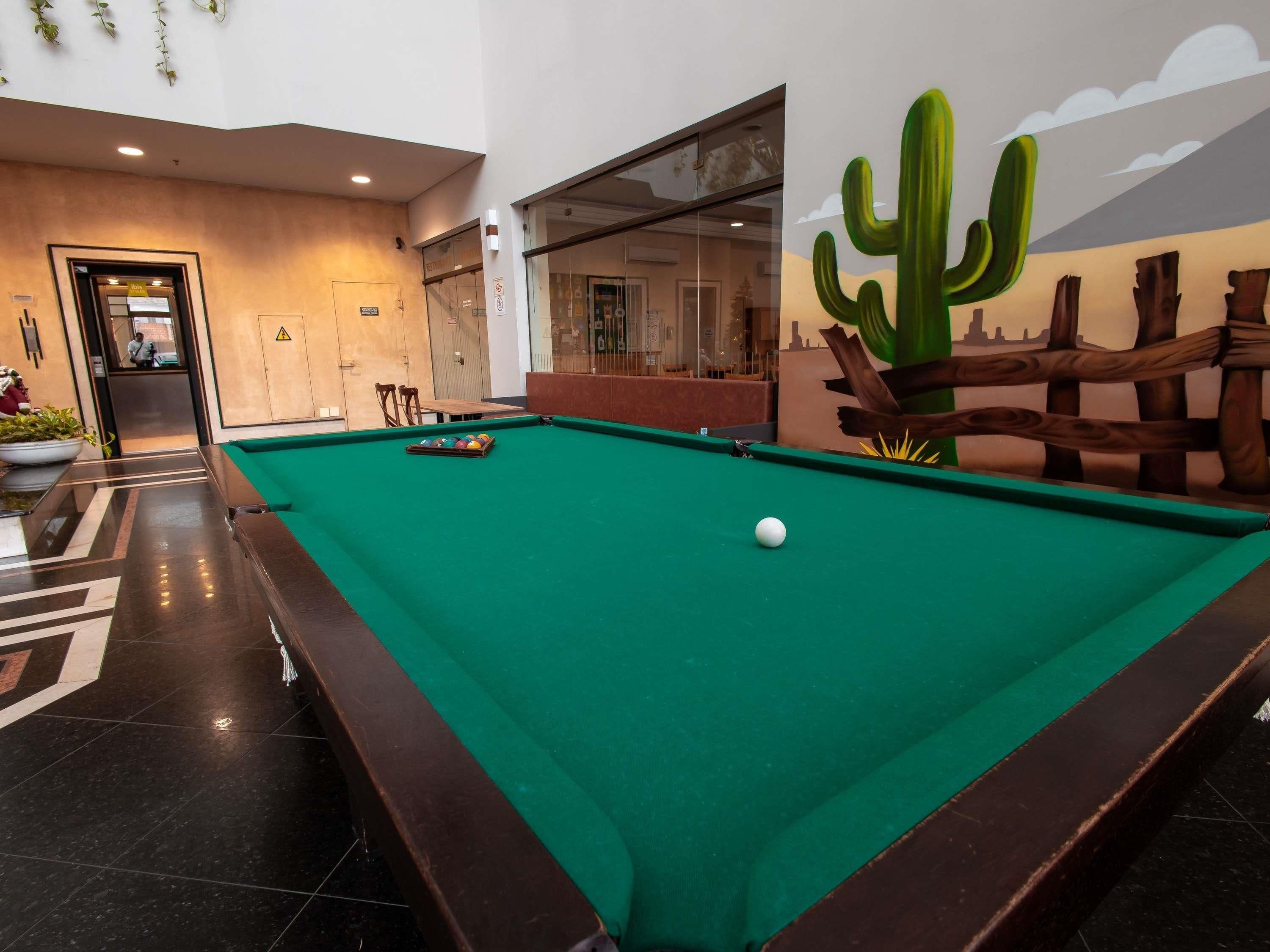 A pool table with balls, a cactus mural, and a wooden fence.