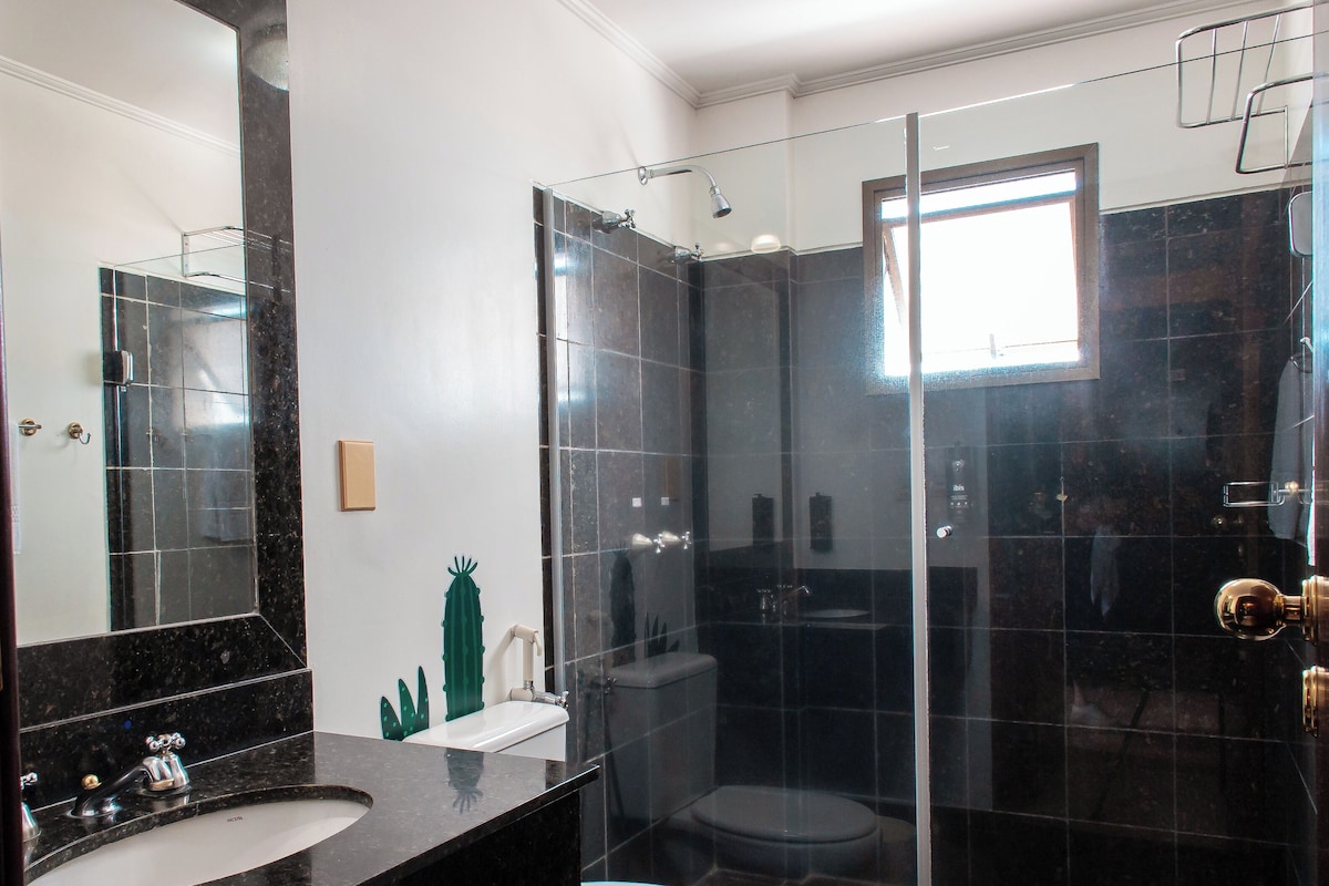 A modern bathroom with a glass-enclosed shower, a large mirror, and a marble countertop.