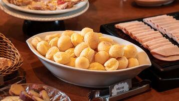 En buffet med forskellige spiser, herunder en skål med ostebolde, skiveskåret skinke og en tallerken med grøntsager.