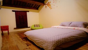 A bedroom with a wooden floor, a bed with a star-patterned bedspread, a green bean bag chair, and a red door. - Pearl B&B (Jinsha)