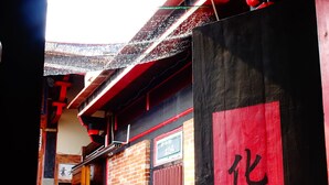 A traditional building with a red and black facade, a wooden door with Chinese characters, and a variety of potted plants outside. - Pearl B&B (Jinsha)