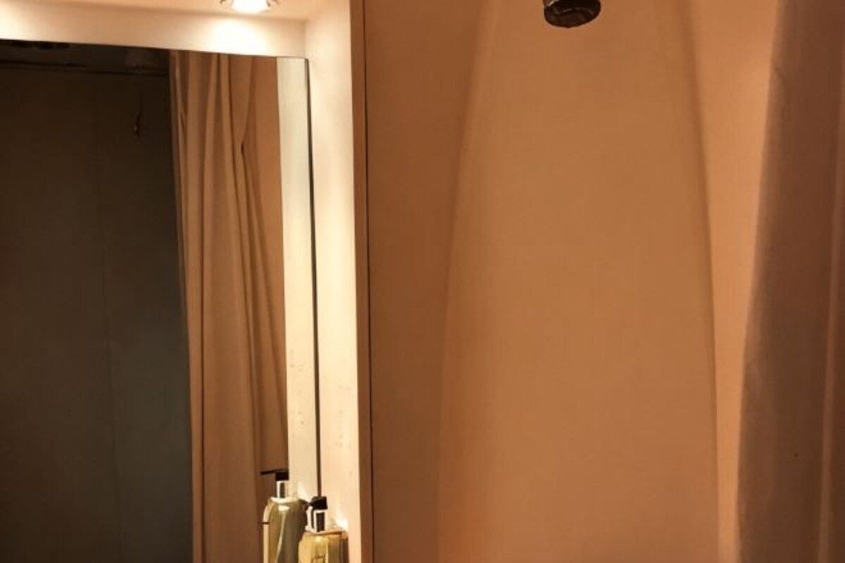 A bathroom with a mirror, a towel rack, and a bottle of hand soap.
