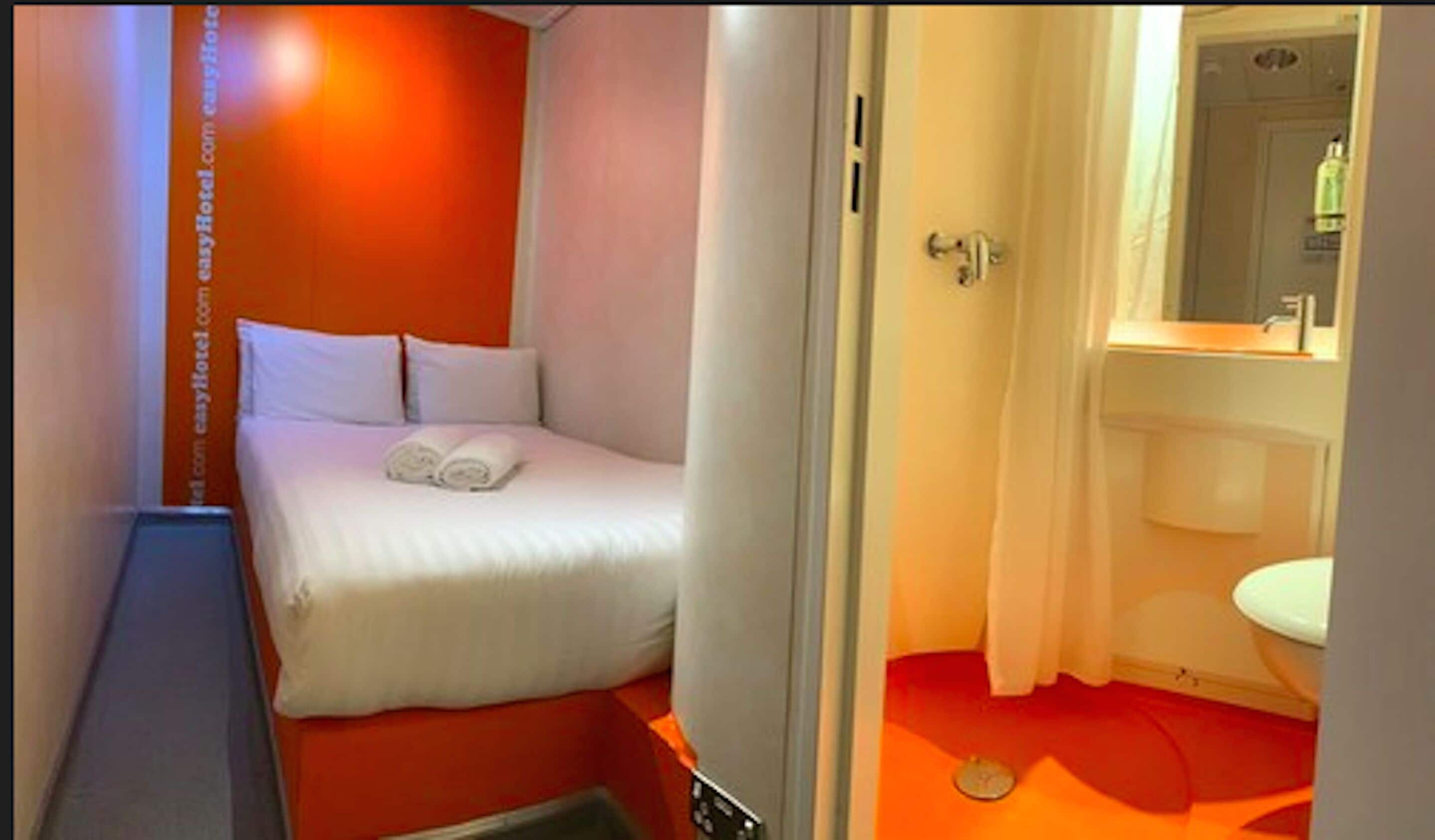 A hotel room with a bed, a small bathroom with a sink, and a mirror.