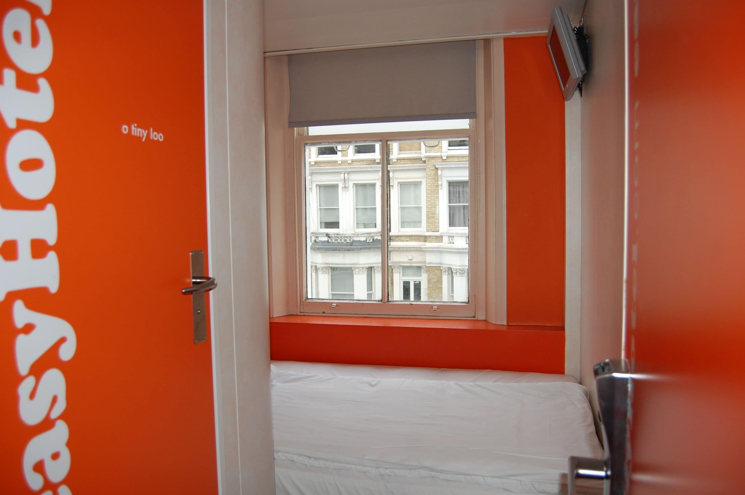 Una habitación con cama, ventana y puerta con un letrero.