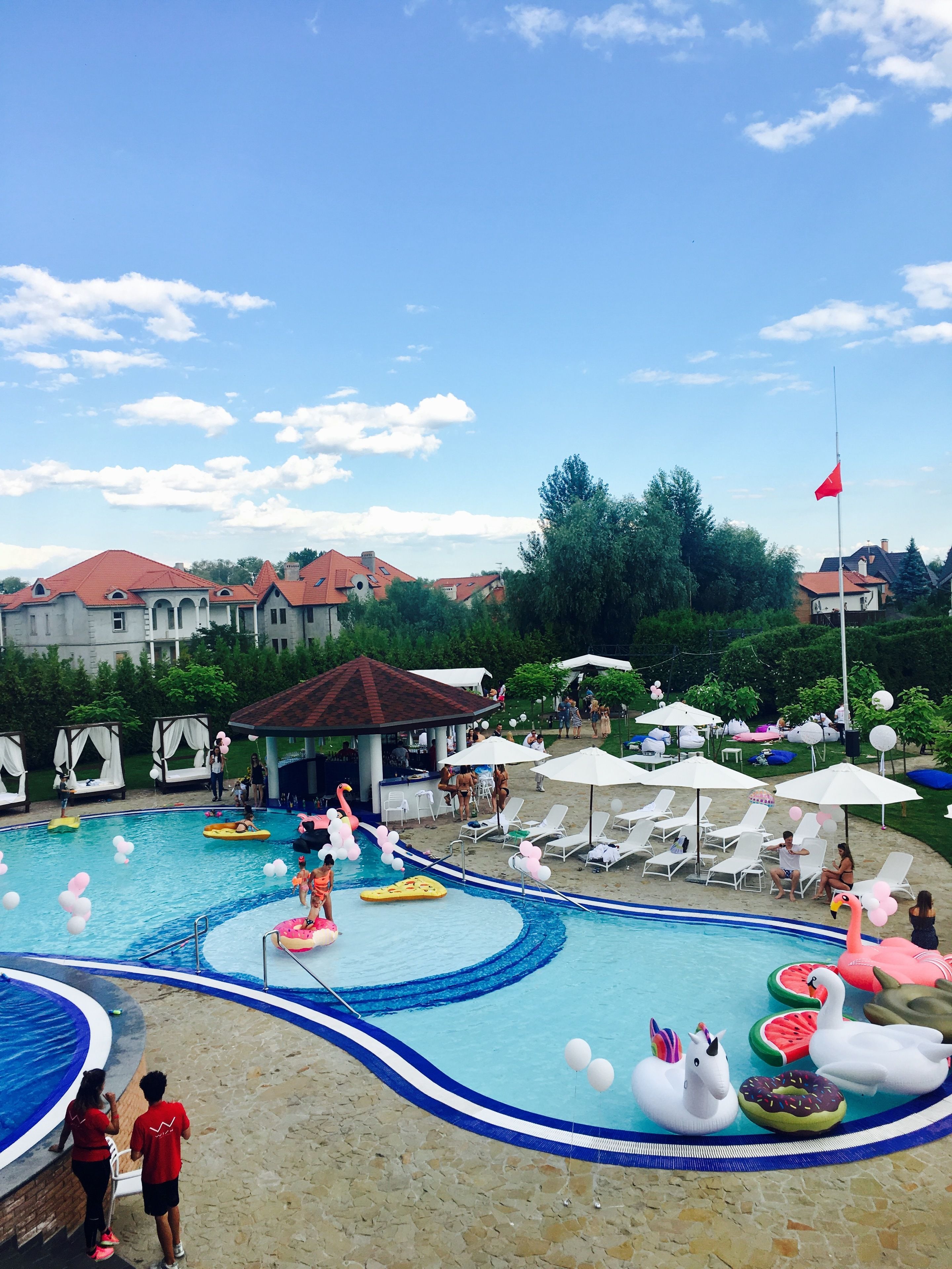 A swimming pool with various inflatable toys, lounge chairs, and umbrellas.