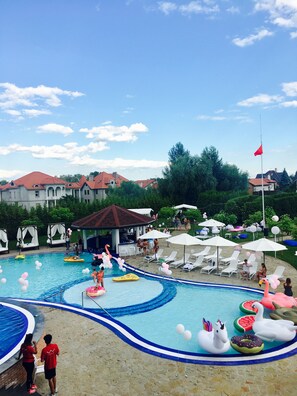 A swimming pool with various inflatable toys, lounge chairs, and umbrellas.