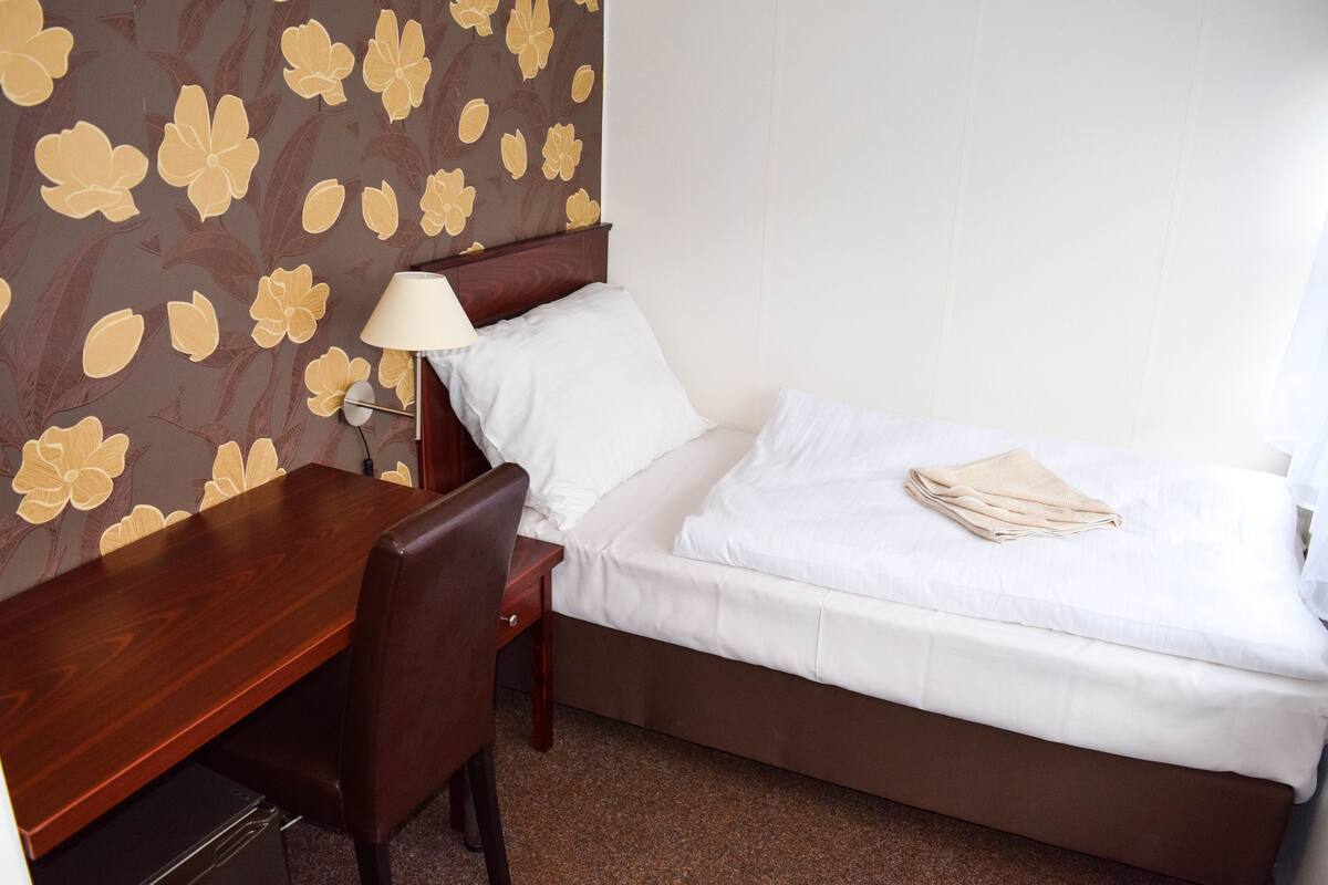 Una habitación de hotel con cama, escritorio, silla y lámpara.
