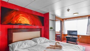 Una habitación de hotel con una cama grande, televisión y un cuadro en la pared.