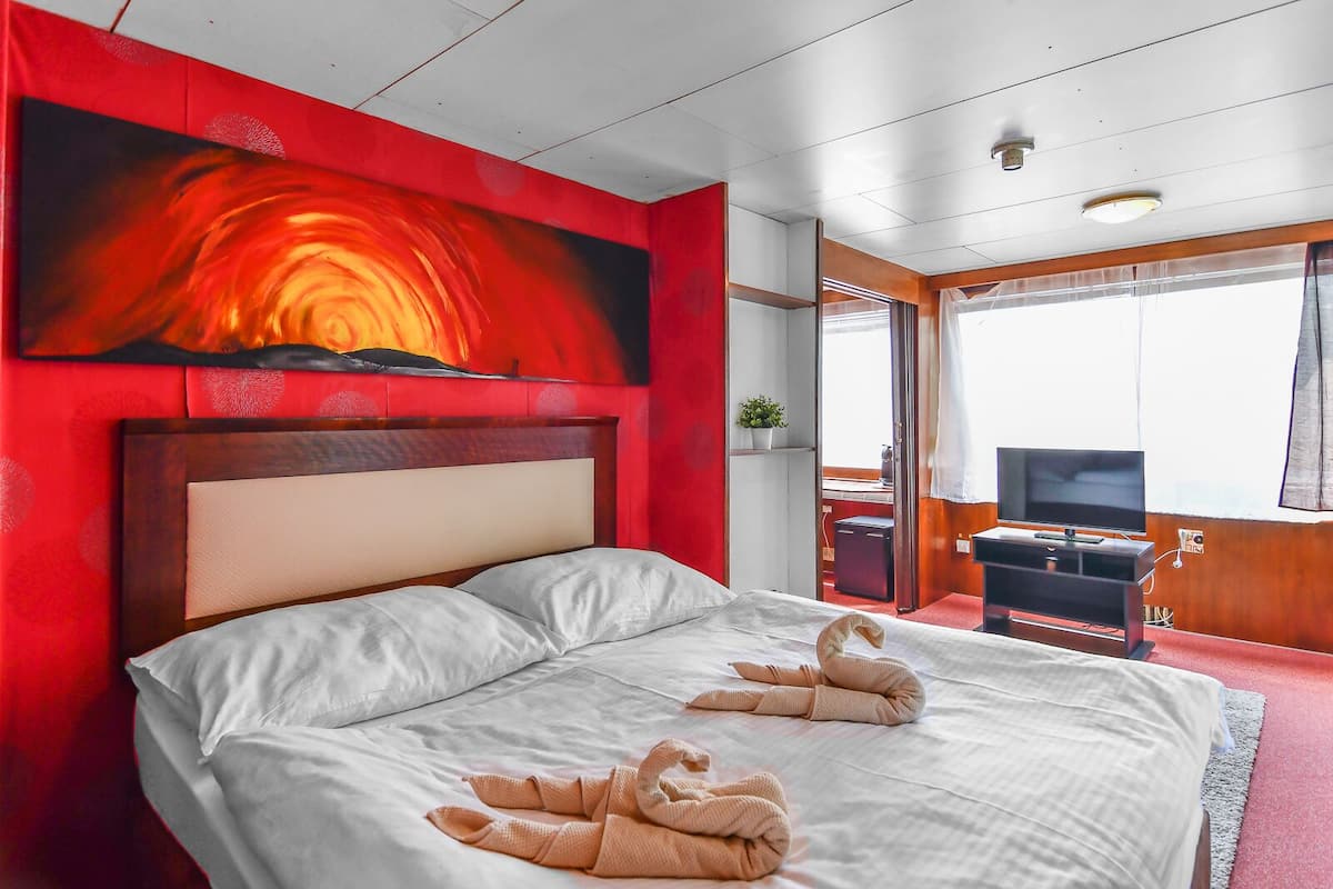 Una habitación de hotel con una cama grande, televisión y un cuadro en la pared.