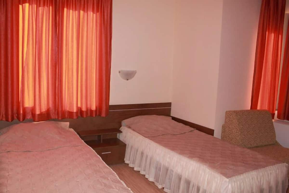 Una habitación con dos camas individuales, una silla y una lámpara fijada a la pared.
