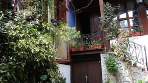 A traditional building with a wooden door, a balcony with potted plants, and a stone wall. - Alafrangite Hotel (Plovdiv)