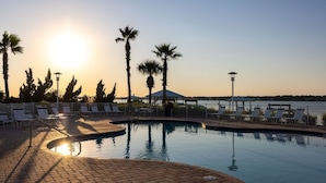 A poolside area with lounge chairs and palm trees, overlooking a body of water during sunset. - Mustique 901 (Gulf Shores)