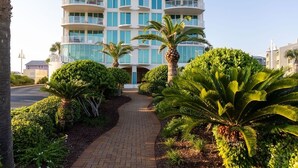 A multi-story hotel with balconies, surrounded by well-maintained landscaping including palm trees and shrubs. - Mustique 901 (Gulf Shores)