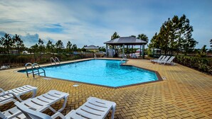 A rectangular swimming pool with a tiled deck, surrounded by white lounge chairs and a covered pavilion. - The Rookery III Unit 4001 (Gulf Shores)