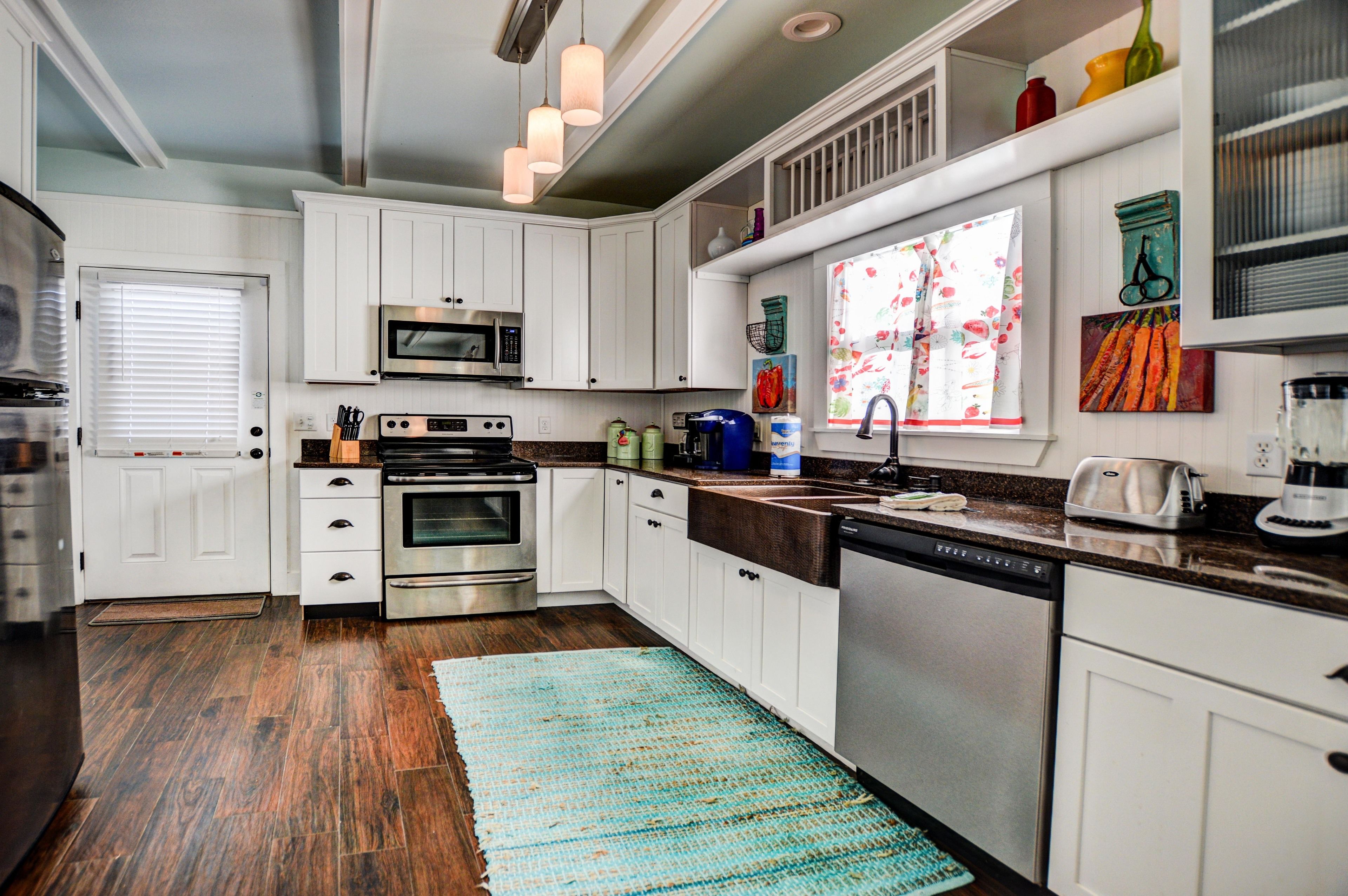 A modern kitchen with white cabinets, stainless steel appliances, and a blue patterned rug.