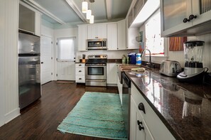 Enjoy cooking in this well-equipped kitchen with stainless steel appliances, white cabinetry, and a granite countertop.